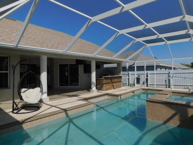 view of pool featuring exterior bar, a patio area, an in ground hot tub, and glass enclosure