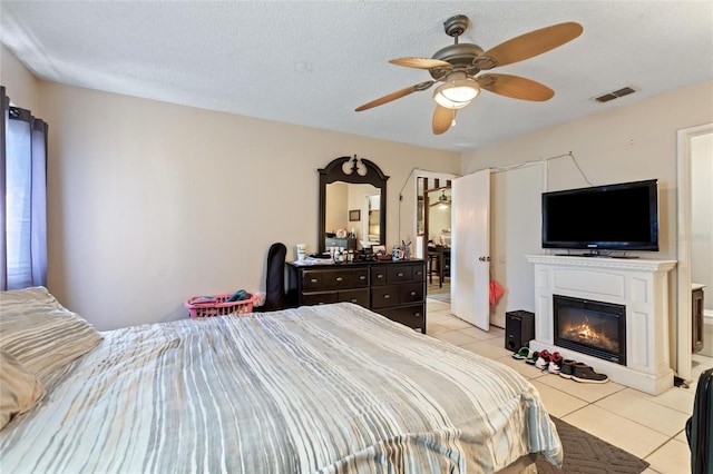 bedroom with ceiling fan, light tile patterned floors, and a textured ceiling