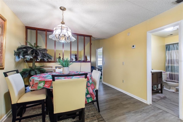 dining room featuring hardwood / wood-style floors, a textured ceiling, and a notable chandelier