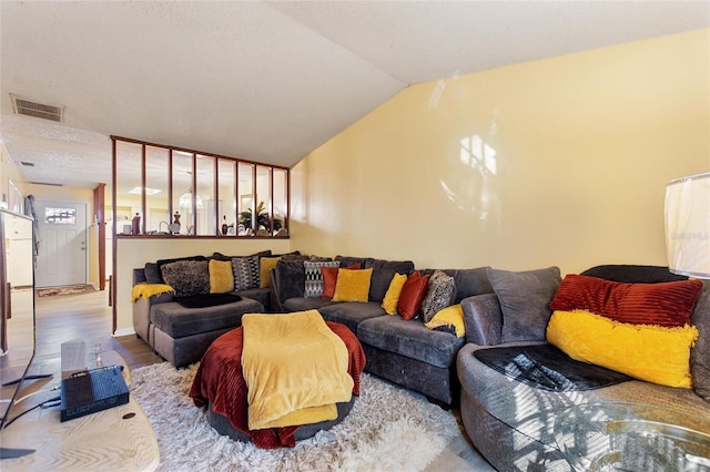 living room featuring hardwood / wood-style flooring, a textured ceiling, and vaulted ceiling