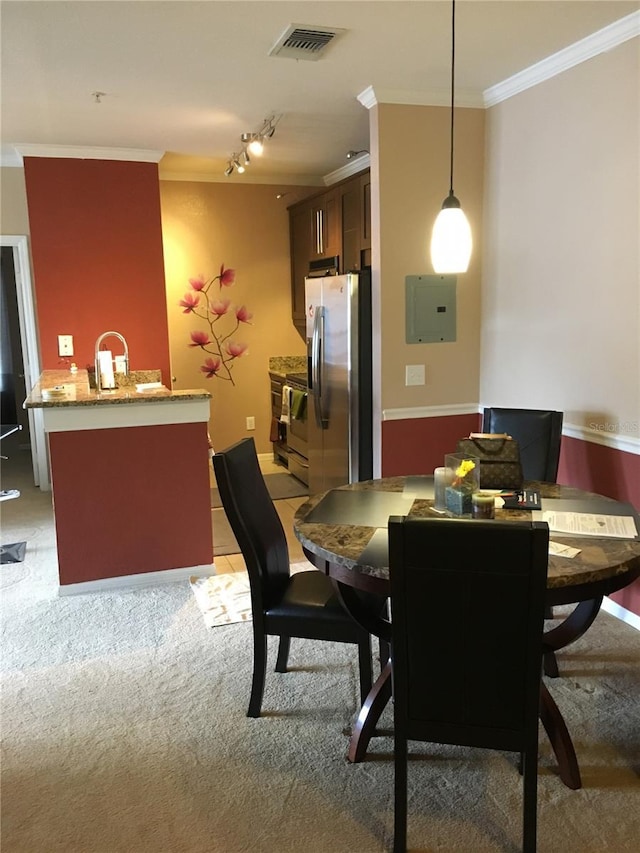 carpeted dining room featuring electric panel, crown molding, and rail lighting