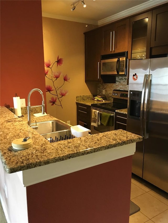 kitchen with dark brown cabinetry, sink, stainless steel appliances, backsplash, and light tile patterned flooring