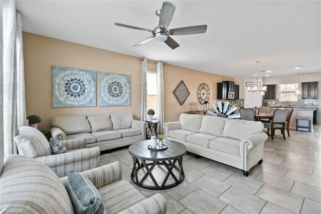 living room with ceiling fan with notable chandelier and light tile patterned floors