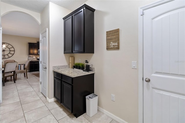 interior space with decorative backsplash, light tile patterned floors, and light stone countertops