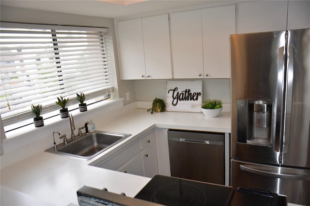 kitchen featuring stainless steel appliances, white cabinets, light countertops, and a sink