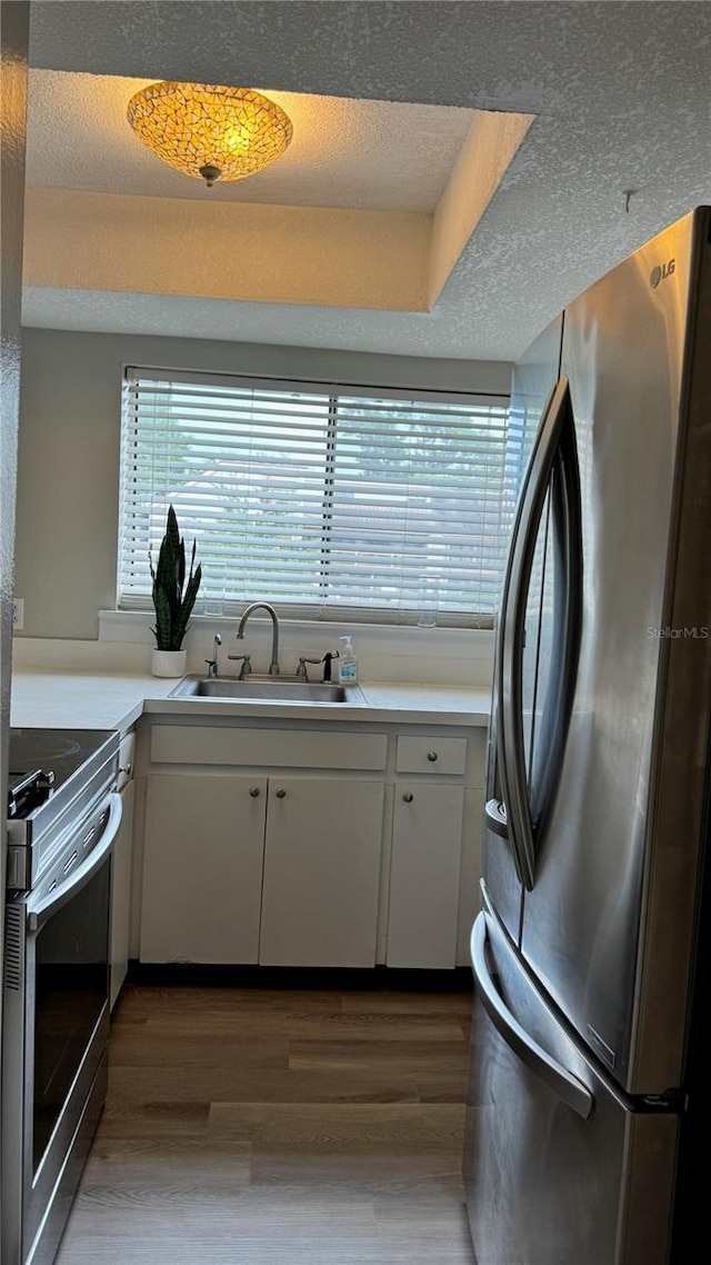 kitchen with a sink, stainless steel appliances, light countertops, and white cabinets