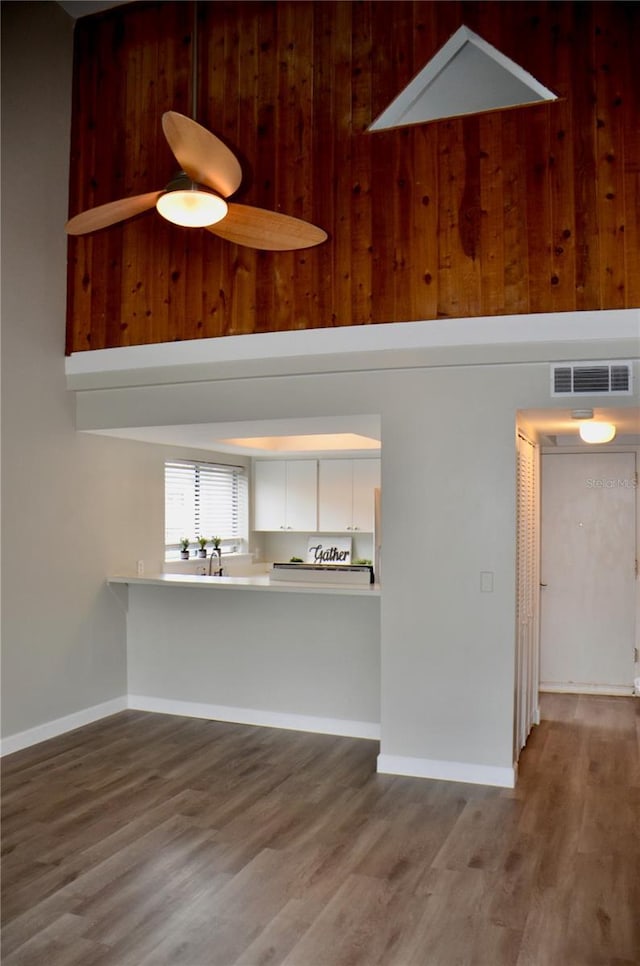 unfurnished living room featuring light wood-style floors, visible vents, and a towering ceiling