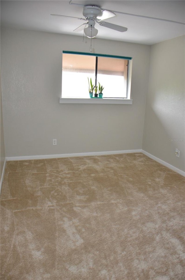 spare room with ceiling fan, baseboards, and light colored carpet