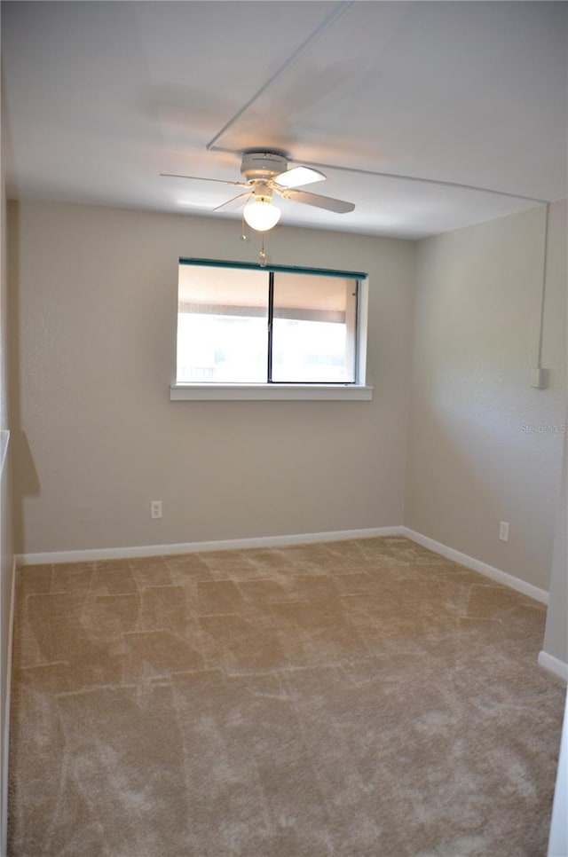 empty room featuring light carpet, a ceiling fan, and baseboards