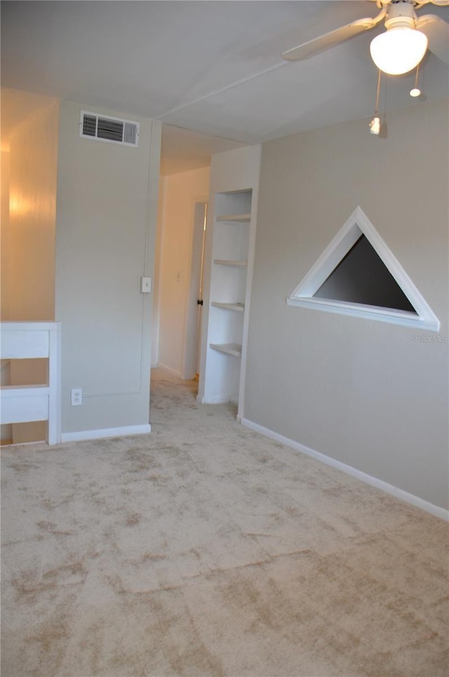 carpeted spare room with baseboards, visible vents, and a ceiling fan