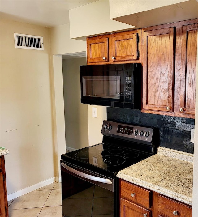 kitchen featuring decorative backsplash, light stone countertops, light tile patterned flooring, and black appliances