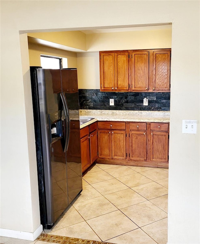 kitchen featuring backsplash, black fridge, and light tile patterned flooring