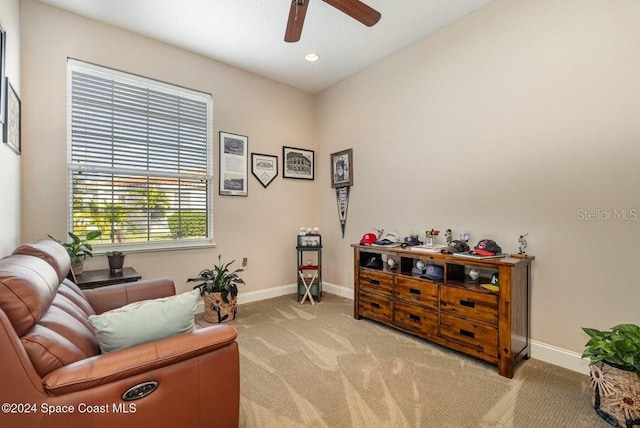 living area with light carpet and ceiling fan