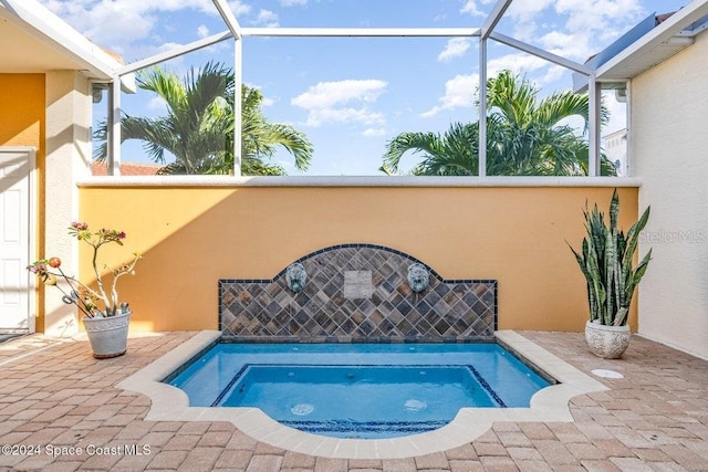 view of pool with glass enclosure, an in ground hot tub, and a patio