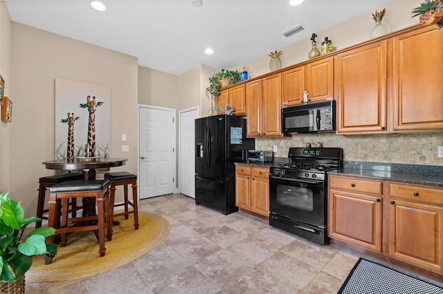 kitchen featuring black appliances, decorative backsplash, and dark stone counters