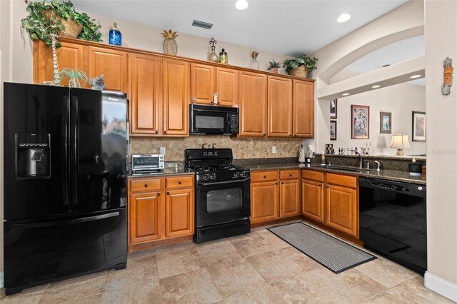 kitchen with dark stone countertops, decorative backsplash, sink, and black appliances