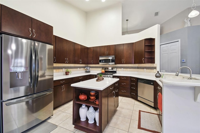 kitchen with a kitchen island, light tile patterned flooring, stainless steel appliances, and high vaulted ceiling