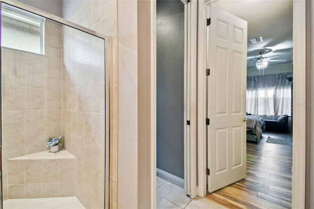 bathroom with walk in shower, hardwood / wood-style floors, plenty of natural light, and ceiling fan