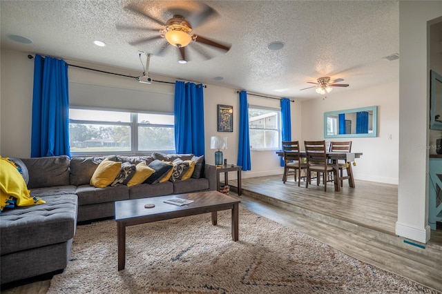 living room featuring hardwood / wood-style floors, ceiling fan, and a textured ceiling