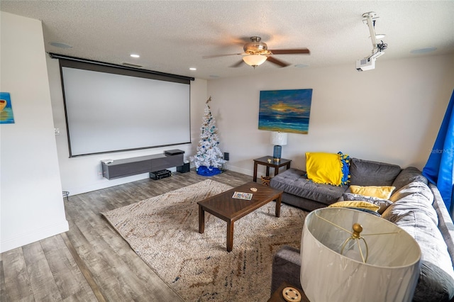 home theater with ceiling fan, wood-type flooring, and a textured ceiling