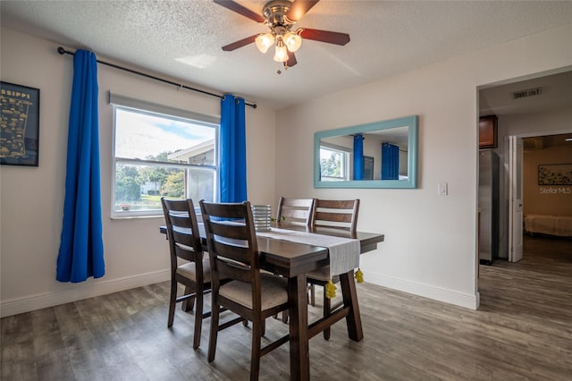 dining space with ceiling fan, dark wood-type flooring, and a textured ceiling