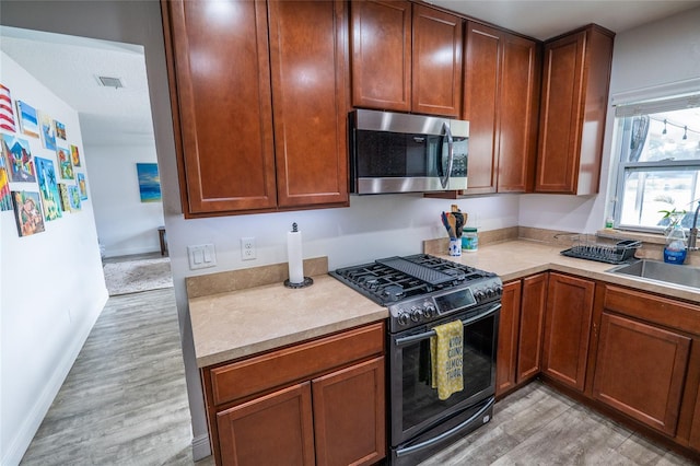 kitchen with light hardwood / wood-style floors, sink, and black gas range oven