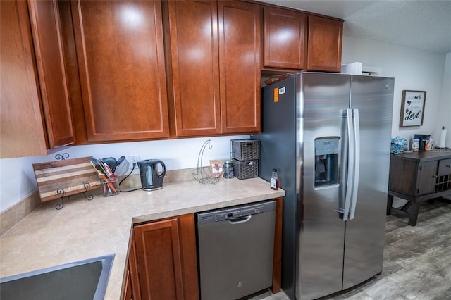 kitchen with light wood-type flooring, appliances with stainless steel finishes, a textured ceiling, and sink