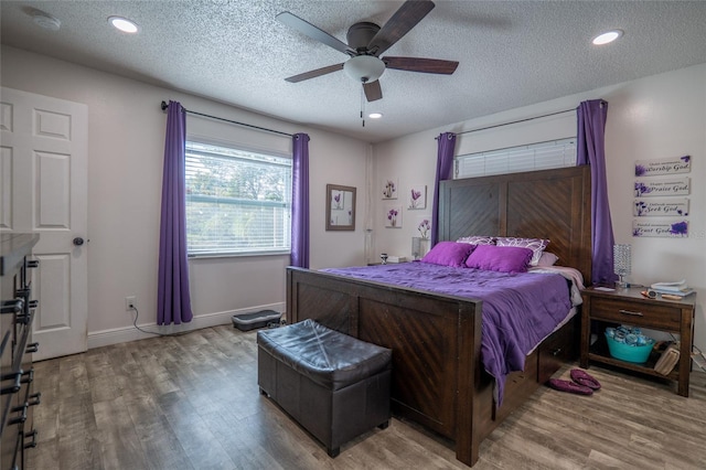 bedroom with hardwood / wood-style floors, ceiling fan, and a textured ceiling