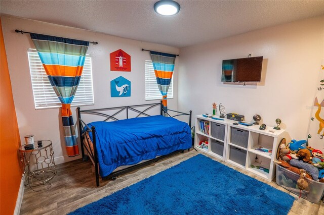 bedroom with hardwood / wood-style floors and a textured ceiling