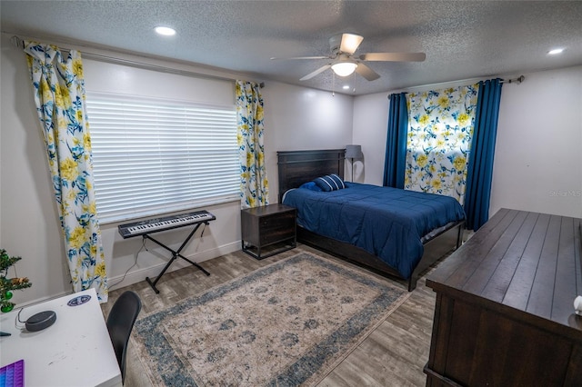 bedroom featuring ceiling fan, wood-type flooring, and a textured ceiling