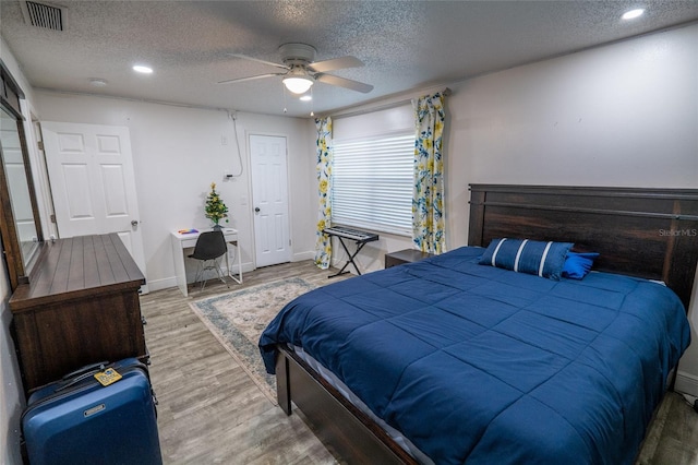 bedroom with hardwood / wood-style floors, ceiling fan, and a textured ceiling