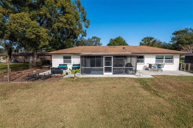 back of house with a sunroom, a patio area, and a lawn