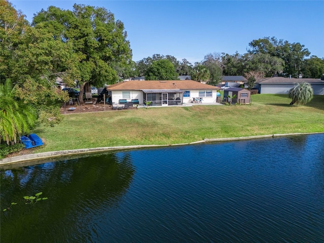 back of house featuring a water view, a storage shed, and a lawn