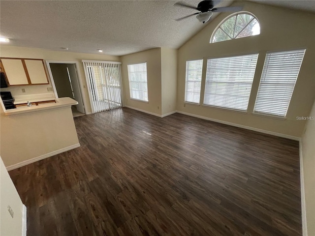 unfurnished living room with a textured ceiling, ceiling fan, lofted ceiling, and dark wood-type flooring