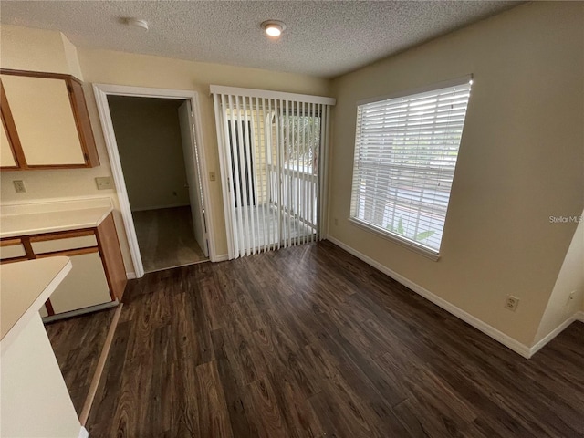 unfurnished dining area featuring dark hardwood / wood-style flooring and a textured ceiling