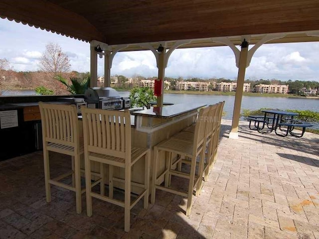 view of patio / terrace featuring area for grilling, a water view, exterior bar, and grilling area