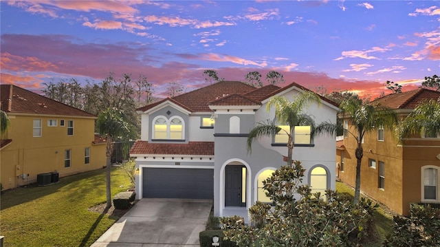 mediterranean / spanish house featuring a garage, a yard, and central AC unit