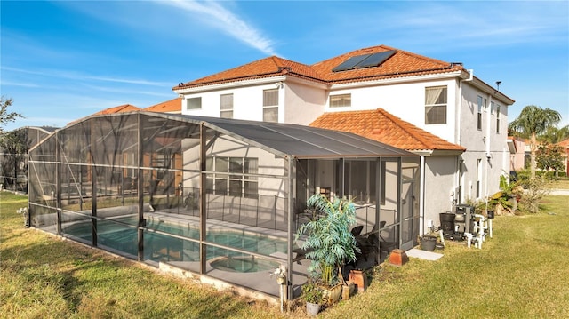 back of property featuring a yard, a lanai, a fenced in pool, and solar panels