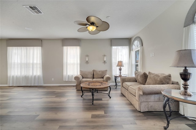 living room featuring ceiling fan, wood-type flooring, and a textured ceiling