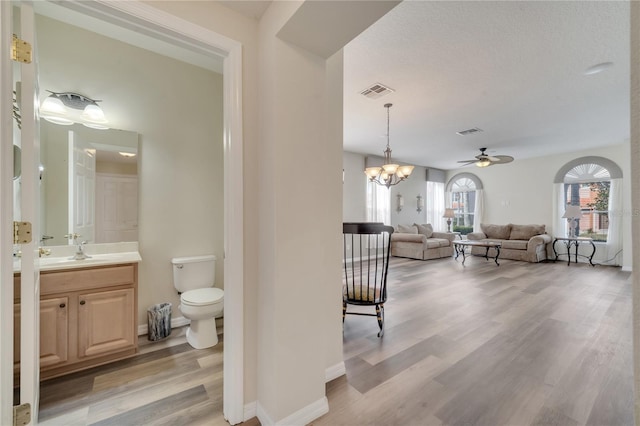 bathroom featuring hardwood / wood-style flooring, vanity, an inviting chandelier, and toilet