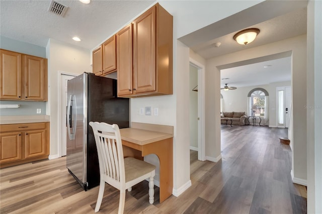 kitchen with a textured ceiling, stainless steel fridge, ceiling fan, and light wood-type flooring