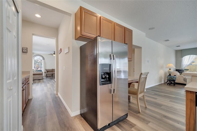 kitchen featuring ceiling fan, stainless steel fridge, light hardwood / wood-style floors, and a textured ceiling