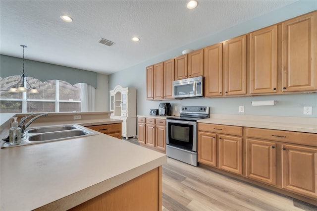 kitchen with sink, decorative light fixtures, a textured ceiling, light wood-type flooring, and appliances with stainless steel finishes