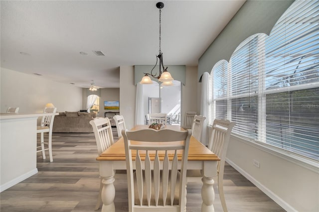 dining room featuring ceiling fan with notable chandelier and wood-type flooring