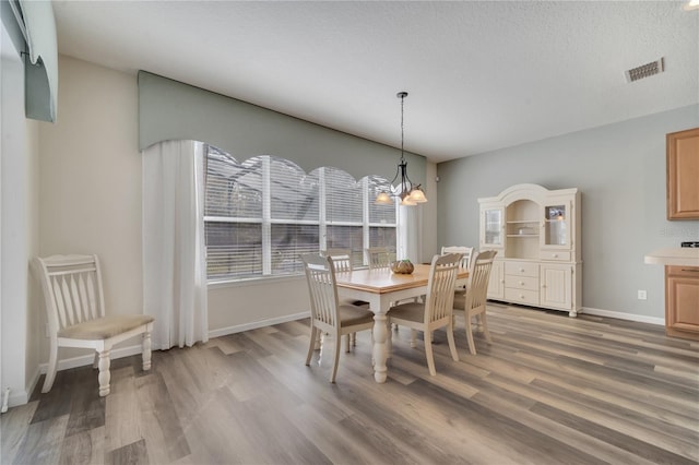 dining space with an inviting chandelier, hardwood / wood-style flooring, and a textured ceiling