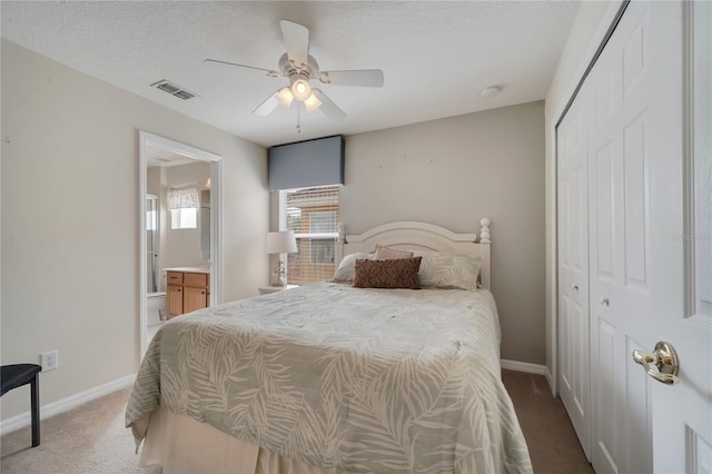 carpeted bedroom featuring ceiling fan, ensuite bath, a closet, and a textured ceiling