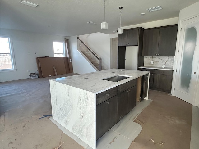 kitchen featuring tasteful backsplash, dark brown cabinets, sink, pendant lighting, and a kitchen island