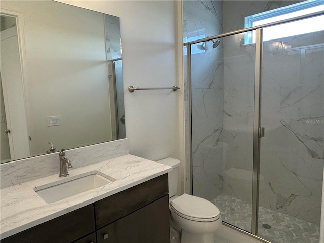 bathroom featuring an enclosed shower, vanity, and toilet