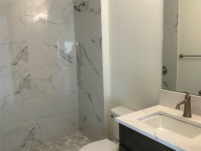 bathroom with vanity, toilet, and a tile shower