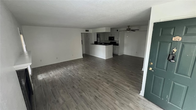 unfurnished living room featuring hardwood / wood-style flooring, ceiling fan, and a textured ceiling